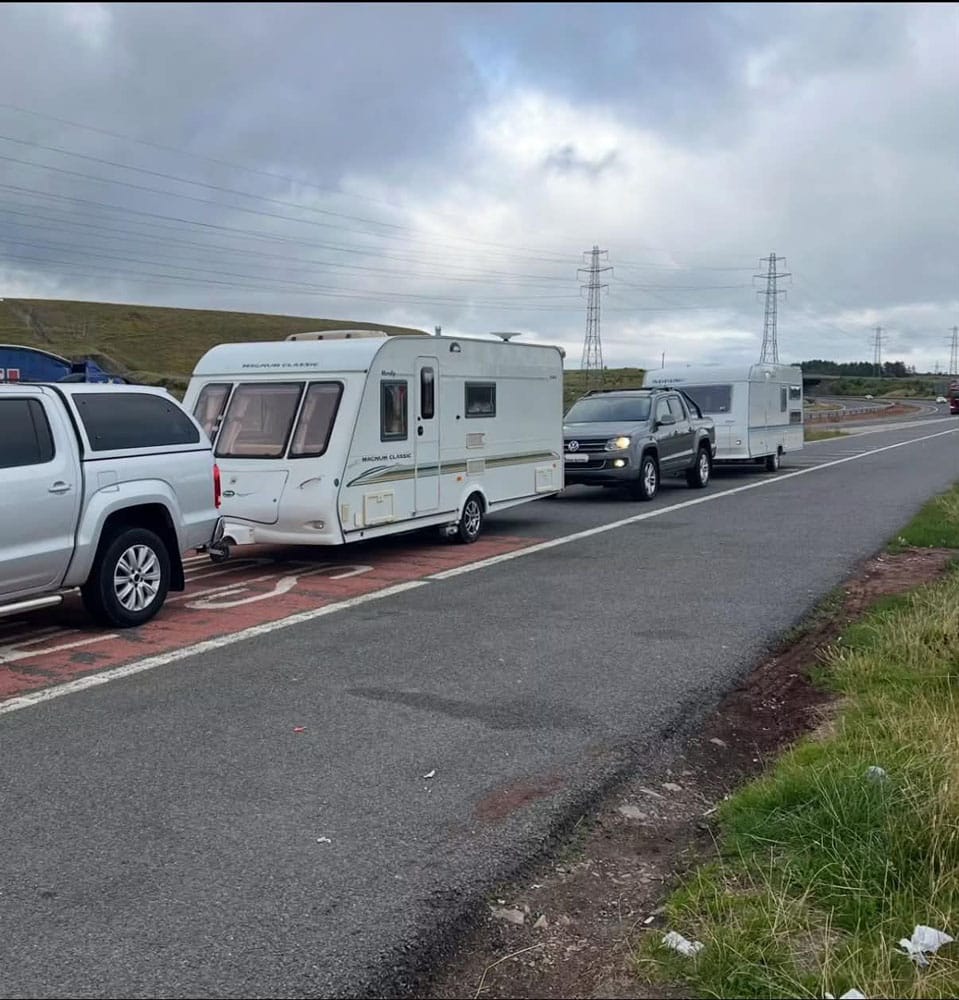 Two touring caravans including a Compass Magnum Classic being collected roadside by pickup trucks