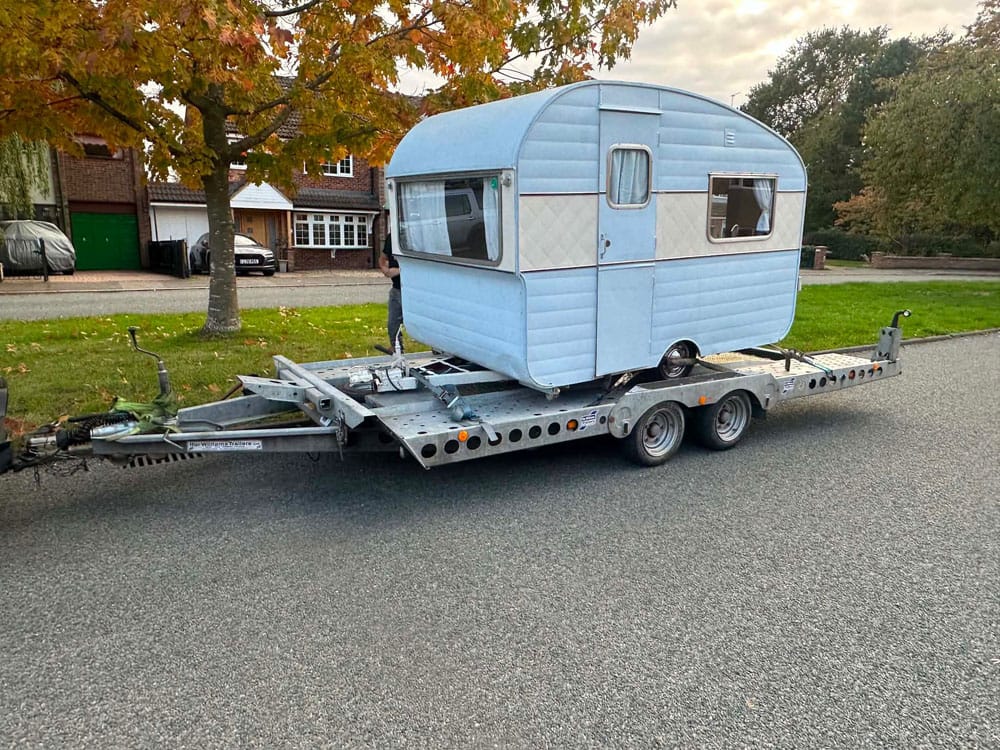 Vintage two-tone blue caravan loaded on a transporter trailer ready for collection